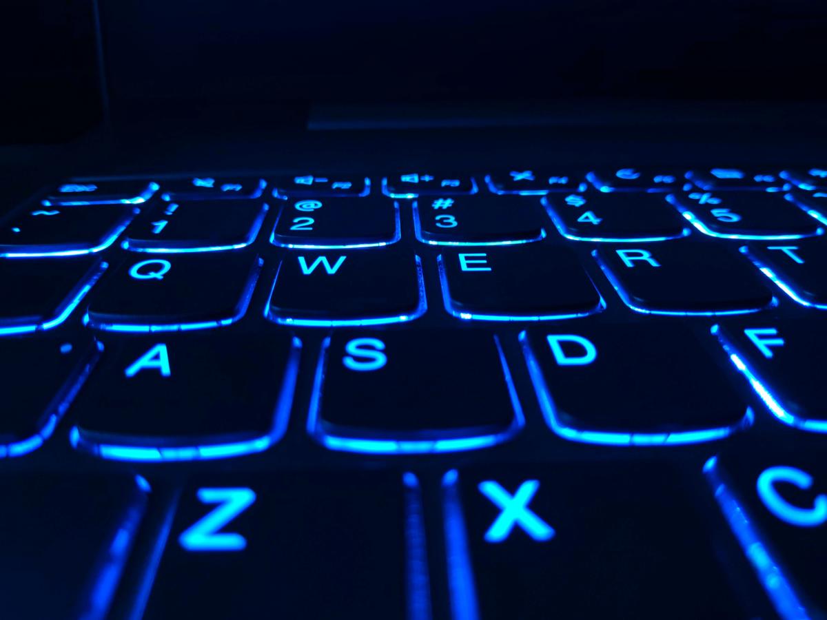 An image of a futuristic robotic humanoid sitting at a desk and typing on a computer keyboard