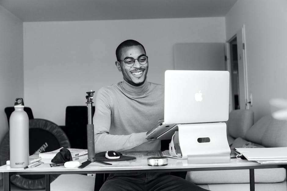An image of a person sitting at a desk and working on a computer while smiling and looking satisfied.