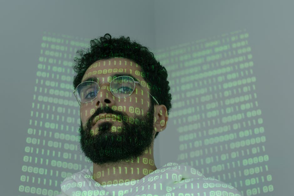 An image showing a person looking concerned while working on a computer behind a wall of binary code.